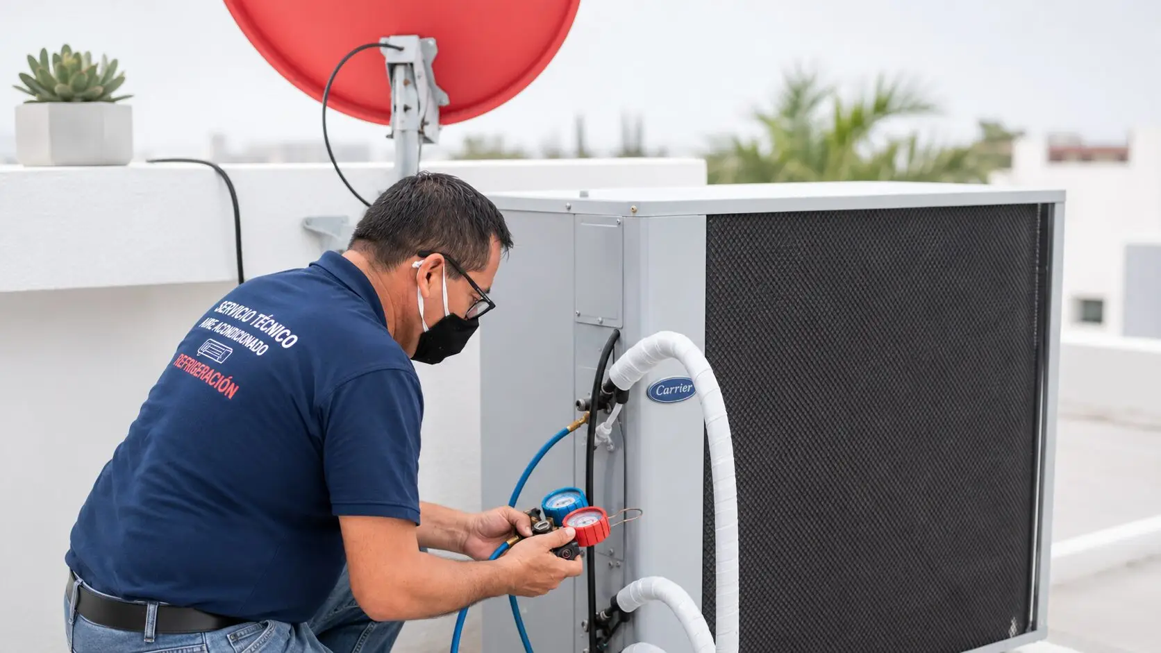 HVAC technician checks pressure gauges while servicing a rooftop air-conditioning unit in a bright, modern setting with clean white surfaces and red-and-blue accents.
